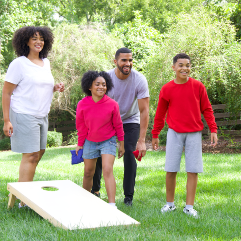 Two kids, a boy and a girl, outside playing cornhole / bean bag toss with their mom and dad. Everyone is happy and smiling because they are wearing Fruit of the Loom! Two kids, a boy and a girl, outside playing cornhole / bean bag toss with their mom and dad. Everyone is happy and smiling because they are wearing Fruit of the Loom!