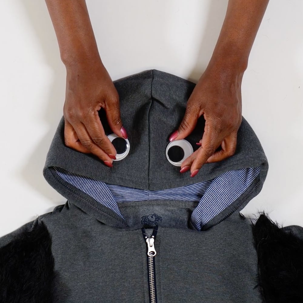 adding googly eyes to the hood of the sweatshirt for the spider
